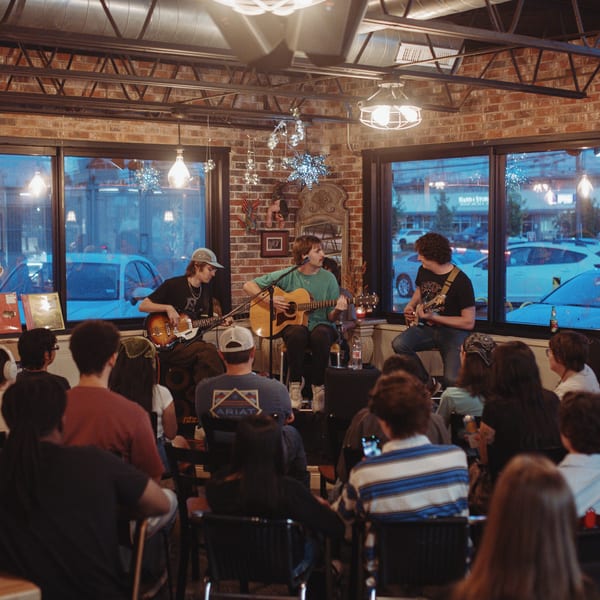 A band performs live music for a seated audience in a cozy restaurant at night.