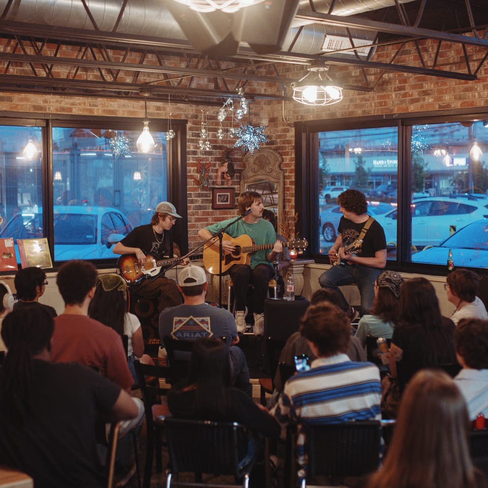 A band performs live music for a seated audience in a cozy restaurant at night.